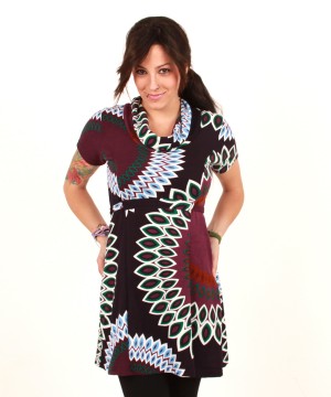 Kobieta w tunice z wzorem w liście i geometryczne kształty, ręce w kieszeniach, na białym tle.