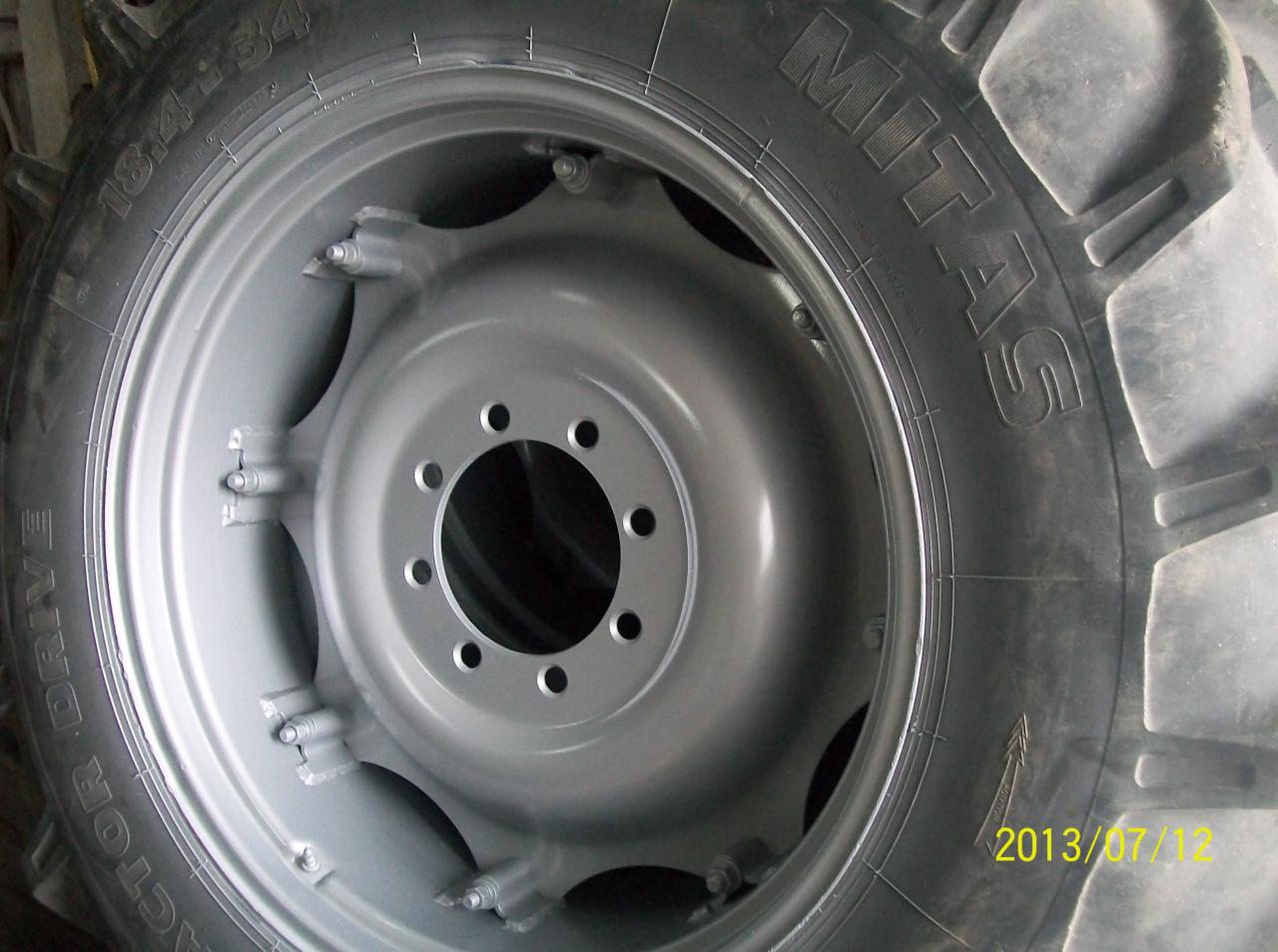 Szara opona Mitas 18.4-34 z felgą, prawdopodobnie od ciągnika rolniczego, po renowacji lub malowaniu. Widoczny bieżnik i data 2013/07/12.