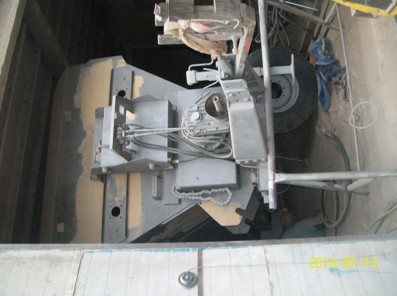 Wnętrze studni kręgowej z widocznym sprzętem do pogłębiania, oświetlonym od góry. Elementy metalowe w kolorze szarym, widoczne kable i rury.