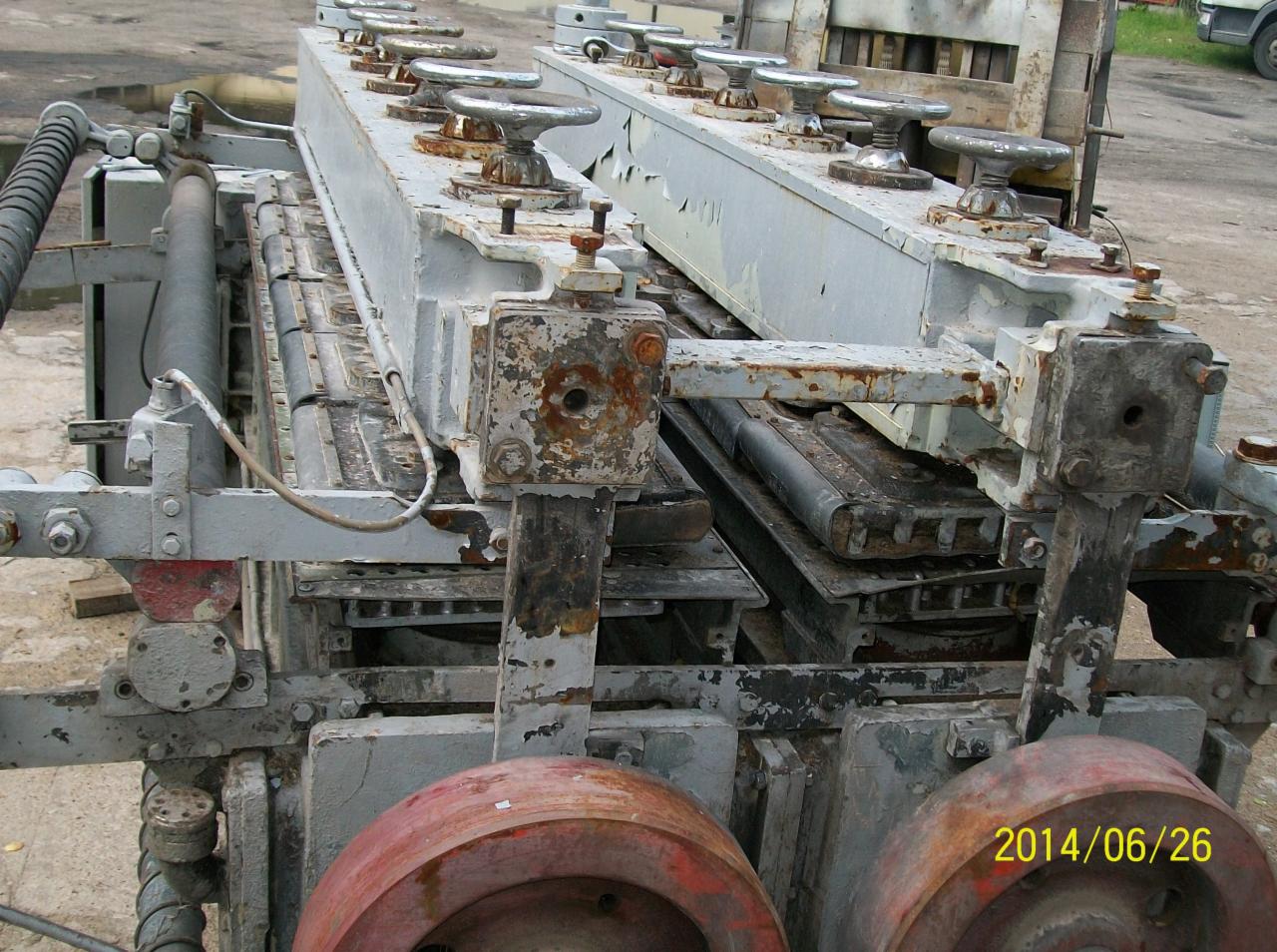 Szara, metalowa konstrukcja maszyny z rdzawymi elementami i pokrętłami, widoczna data 2014/06/26. Maszyna wygląda na starą i zużytą.
