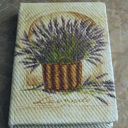 Beżowy notes z motywem lawendy w koszyku, stylizowany na haft gobelinowy.