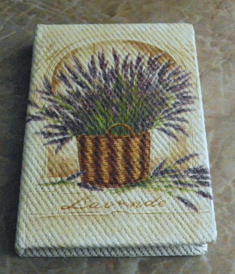 Beżowy notes z motywem lawendy w koszyku, stylizowany na haft gobelinowy.