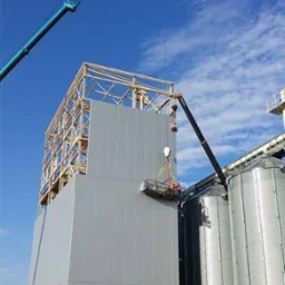 Montaż paneli na konstrukcji stalowej w Dobrzycy, widoczny dźwig i kosz z pracownikami na wysokości.