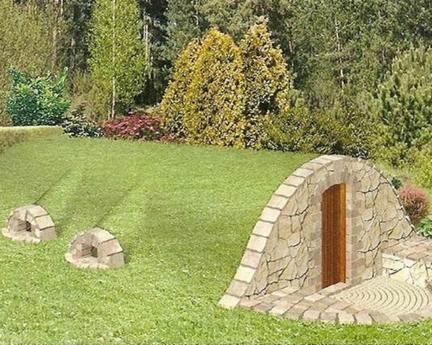 Ziemianka z kamiennym wejściem i dwoma otworami wentylacyjnymi na trawiastym wzgórzu, otoczona drzewami.