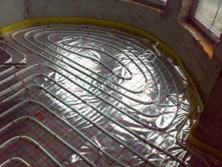 Układanie podłogowego ogrzewania wodnego w Wschowie, rury grzewcze ułożone spiralnie na folii izolacyjnej i siatce zbrojeniowej, przygotowanie do zalania wylewką.