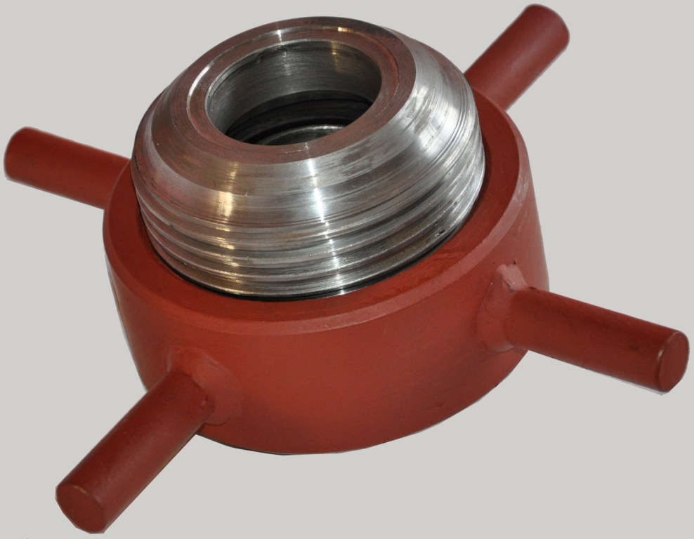 Złączka kulowa do rur stalowych z czterema wypustkami, pomalowana na czerwono-brązowy kolor, widoczne gwintowanie wewnętrzne.