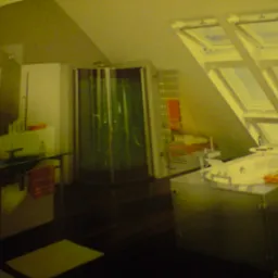 Jasna łazienka na poddaszu ze skośnym sufitem i oknami dachowymi, kabiną prysznicową, umywalką i wanną w obudowie z metalicznym wykończeniem. Pomarańczowe ręczniki dodają koloru.