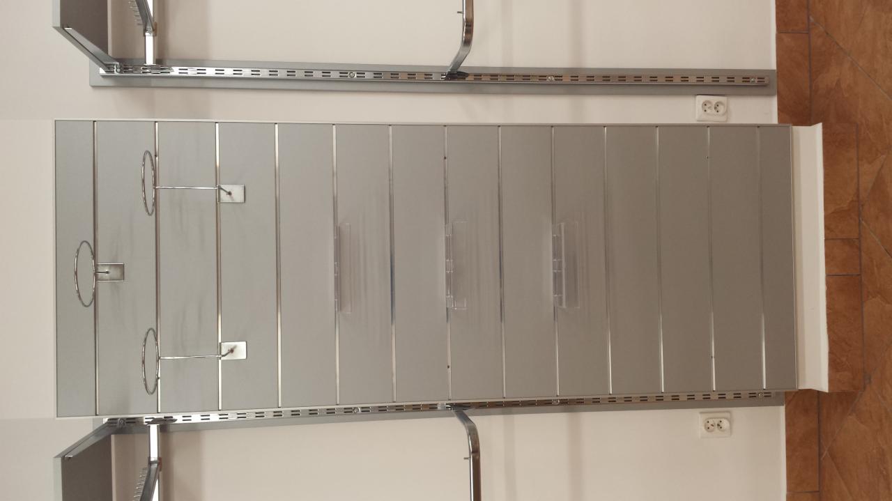 Metalowe panele ścienne z uchwytami na wieszaki, zamontowane na ścianie w sklepie lub magazynie.