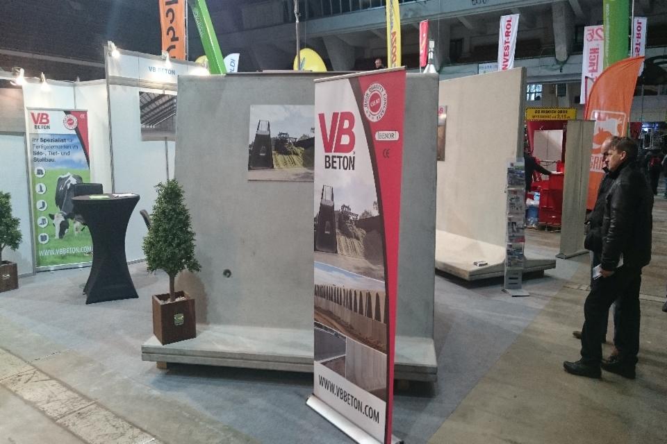 Stoisko targowe z prefabrykatami betonowymi VB Beton, prezentujące zdjęcia silosów i konstrukcji rolniczych, z roll-upem reklamowym i dwoma mężczyznami w tle.