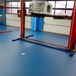 Błękitna podłoga w warsztacie samochodowym z dwoma podnośnikami, jeden z podnośników jest zajęty przez zakryty folią silnik