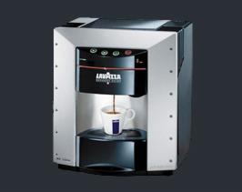 Profesjonalny ekspres do kawy Lavazza z logo, w trakcie parzenia espresso do białego kubka z niebieskim akcentem, na ciemnym tle.