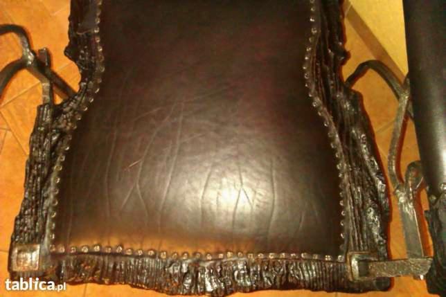 Czarne skórzane siedzisko krzesła z metalową ramą imitującą korę drzewa, zdobione nitami. Widok z góry, bliskie ujęcie na detal wykończenia.