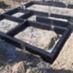 Zalane fundamenty domu jednorodzinnego, widoczne szalunki w kolorze czarnym, przygotowane do dalszych prac budowlanych, ziemia wokół fundamentów.