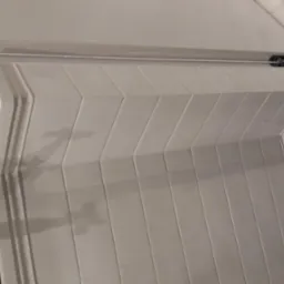 Wykończenie łazienki: Białe, prostokątne płytki ułożone w jodełkę na podwyższeniu kabiny prysznicowej, kontrastujące z heksagonalnymi, grafitowymi płytkami na podłodze.