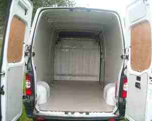 Wnętrze pustej przestrzeni ładunkowej białego busa z otwartymi tylnymi drzwiami, widok od tyłu pojazdu.