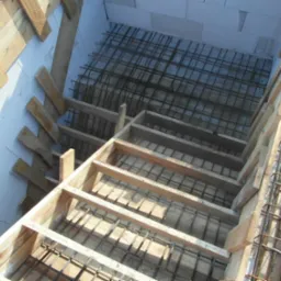 Szalunek z drewna i siatka zbrojeniowa przygotowane do wylania fundamentów pod budynek z bloczków betonu komórkowego.