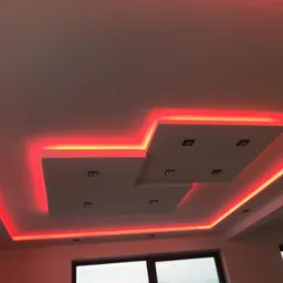 Dekoracyjny sufit podwieszany z oświetleniem LED w kolorze czerwonym i punktowymi lampami, widok od dołu.