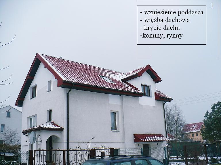 Dwupiętrowy dom z czerwonym dachem pokrytym lekkim śniegiem, widoczny fragment ogrodzenia i samochodu na pierwszym planie, pochmurne niebo w tle.