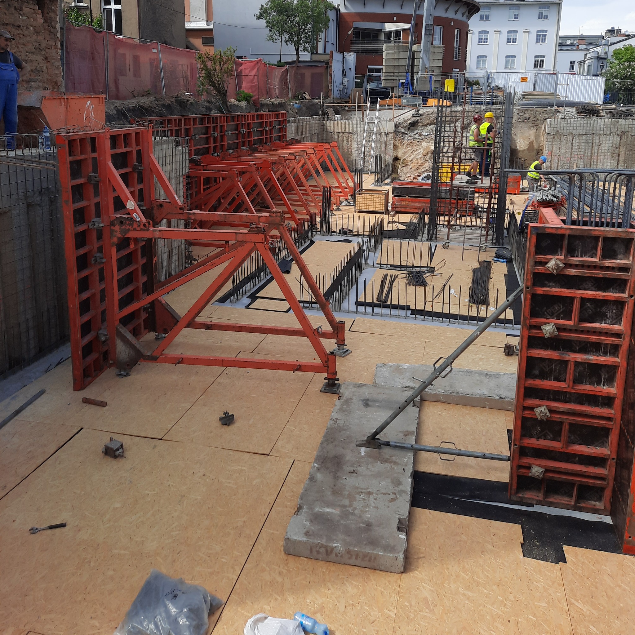 Przygotowanie do betonowania fundamentów: widoczne szalunki, zbrojenie i płyty OSB na budowie.