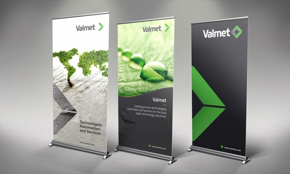 Trzy roll-upy reklamowe firmy Valmet, każdy z innym motywem graficznym: mapa świata z roślin, krople wody na liściu oraz abstrakcyjny zielony znak na czarnym tle.