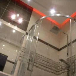 Nowoczesna kabina prysznicowa z chromowanymi elementami, oświetleniem LED w kolorze czerwonym i dekoracyjnymi płytkami w łazience.