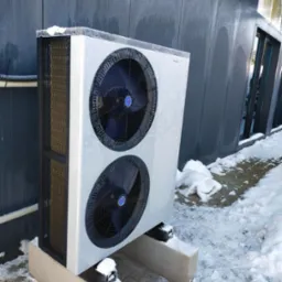 Zewnętrzna jednostka pompy ciepła marki Termet, pokryta szronem, zainstalowana w Redzie na betonowych podstawach, w zimowej scenerii.