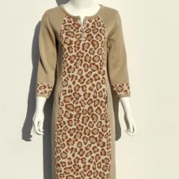 Beżowa dzianinowa sukienka z lampasem w panterkę, zapinana na krótki zamek, prezentowana na manekinie na tle jasnej ściany.