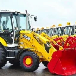 Żółto-biała koparko-ładowarka JCB z czerwonymi felgami i łyżką na parkingu, w tle rząd identycznych maszyn.