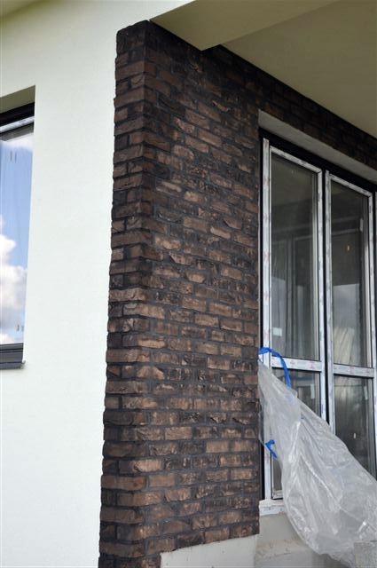 Fragment elewacji budynku z ręcznie formowanej cegły Nelissen Moreno, widoczne okno zabezpieczone folią malarską.