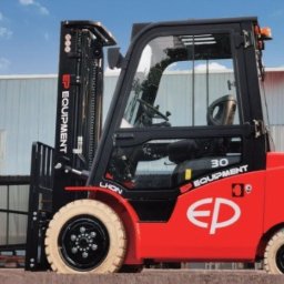 SETMIL Sp. z o.o. - Czerwony, nowy wózek widłowy elektryczny EP Equipment 30 na tle hali magazynowej i błękitnego nieba. Widoczne logo firmy i detale konstrukcyjne.