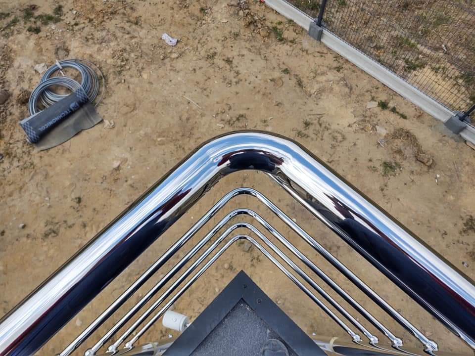 Chromowana balustrada schodowa z rur, widok z góry, na ziemi zwój kabla i opakowanie materiału Technonicol.