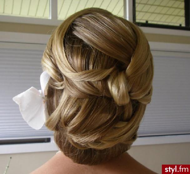 Upięcie włosów blond z wplecioną białą ozdobą kwiatową, widok z tyłu, na jasnym tle.