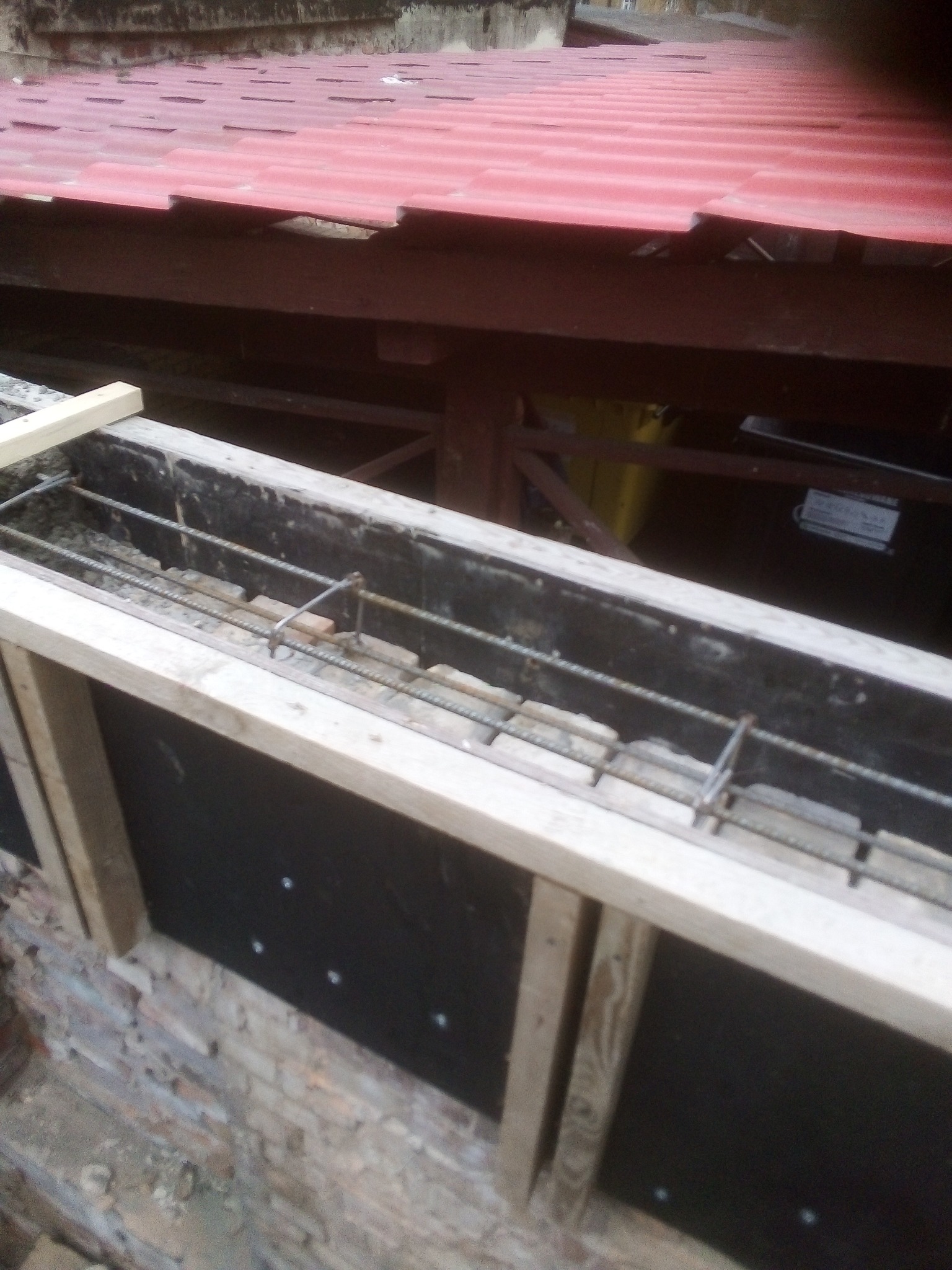 Wzmocnienie fundamentów zbrojeniem i szalunkiem z desek w Gorzowie Wielkopolskim, widoczna izolacja pionowa fundamentu.