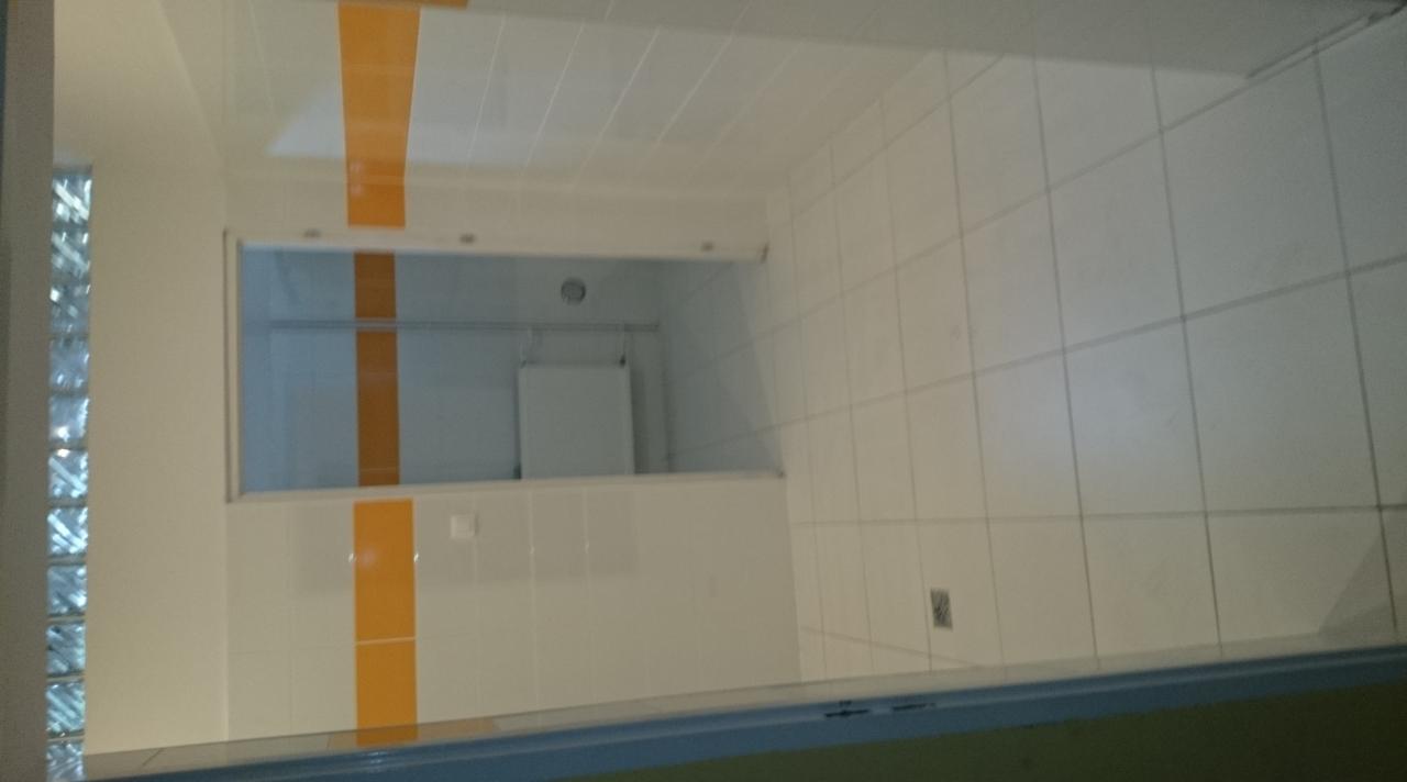 Wykończona łazienka z białymi płytkami i pomarańczowymi akcentami. Widoczna szklana ściana z luksferów i okno w tle, całość w jasnej tonacji.