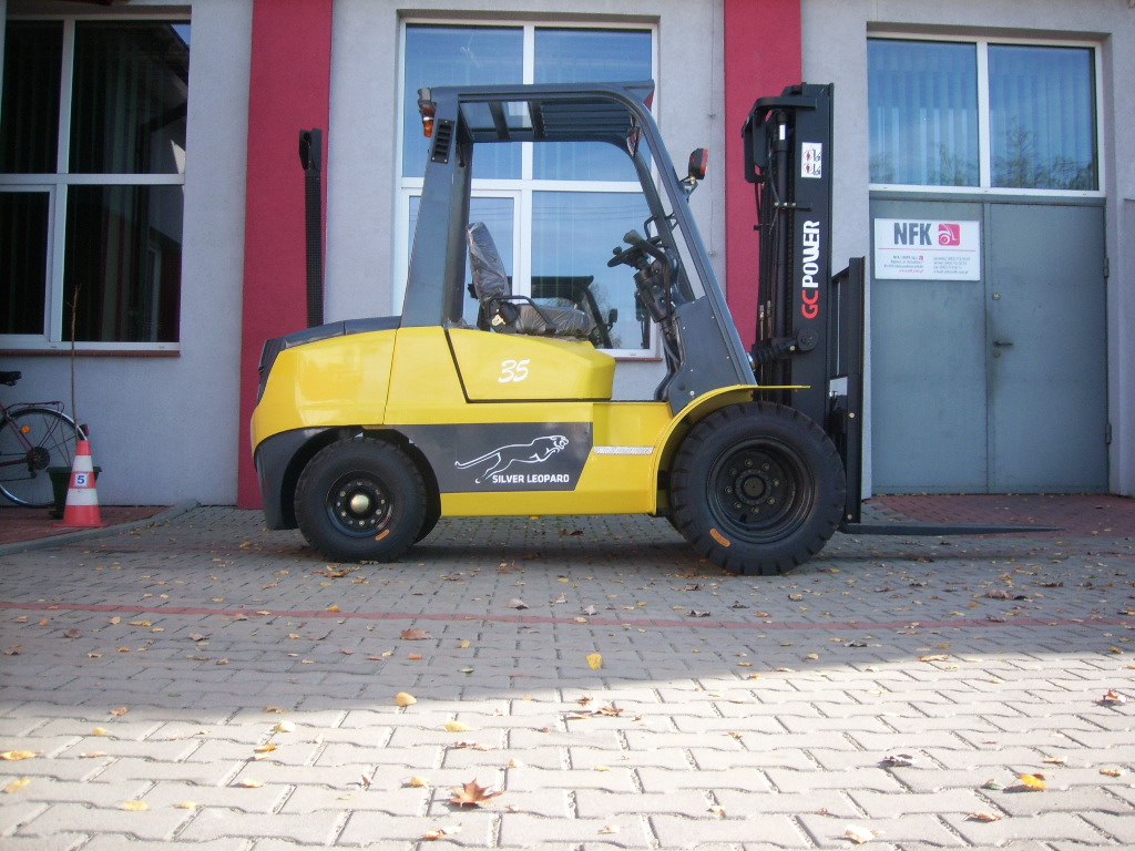 Żółty wózek widłowy GC.POWER FG/FD 35 z czarnym napisem Silver Leopard na tle szarego budynku z czerwonymi akcentami, liście na brukowanej nawierzchni.