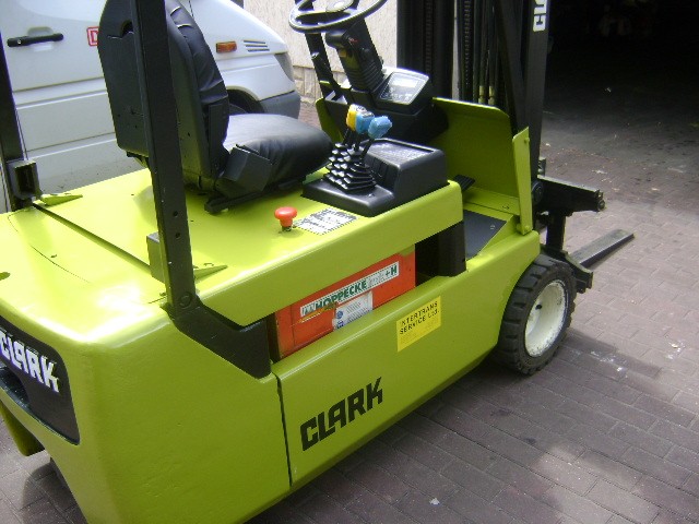 Żółto-zielony wózek widłowy Clark CTM 20 z czarnym siedziskiem i elementami sterującymi, widoczne naklejki informacyjne i opony z białymi ściankami, zaparkowany na brukowanej powierzchni.