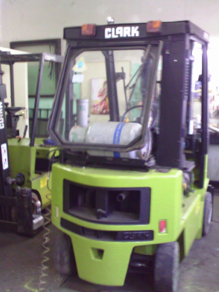 Zielony wózek widłowy Clark GPM 15 z otwartą kabiną, widoczny w warsztacie obok innego wózka widłowego.