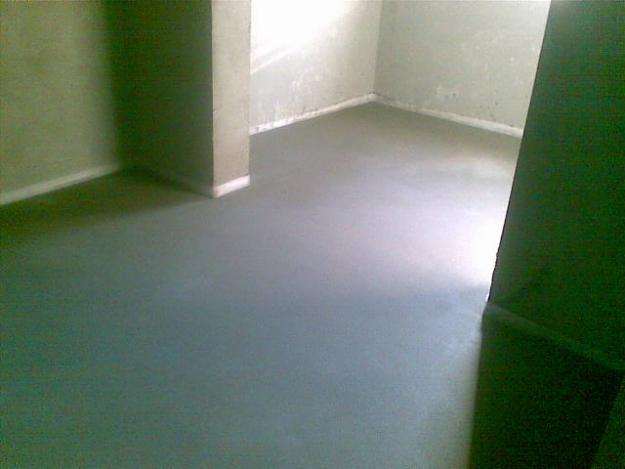 Świeżo wylana, gładka posadzka w pomieszczeniu w Gnieźnie, widok z niskiego kąta, z fragmentem ściany po prawej stronie kadru.