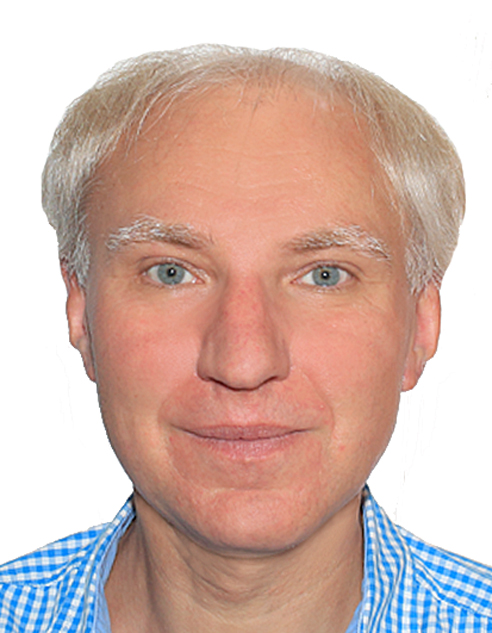 Portret mężczyzny z siwymi włosami i niebieskimi oczami, ubranego w niebiesko-białą koszulę w kratę, na białym tle.