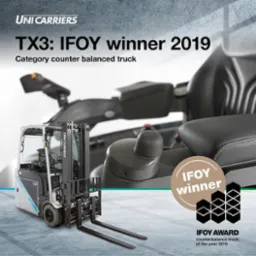 Elektryczny wózek widłowy UniCarriers TX3, zdobywca nagrody IFOY 2019 dla wózków z przeciwwagą, widoczny na tle fragmentów kabiny i fotela operatora oraz logo nagrody.