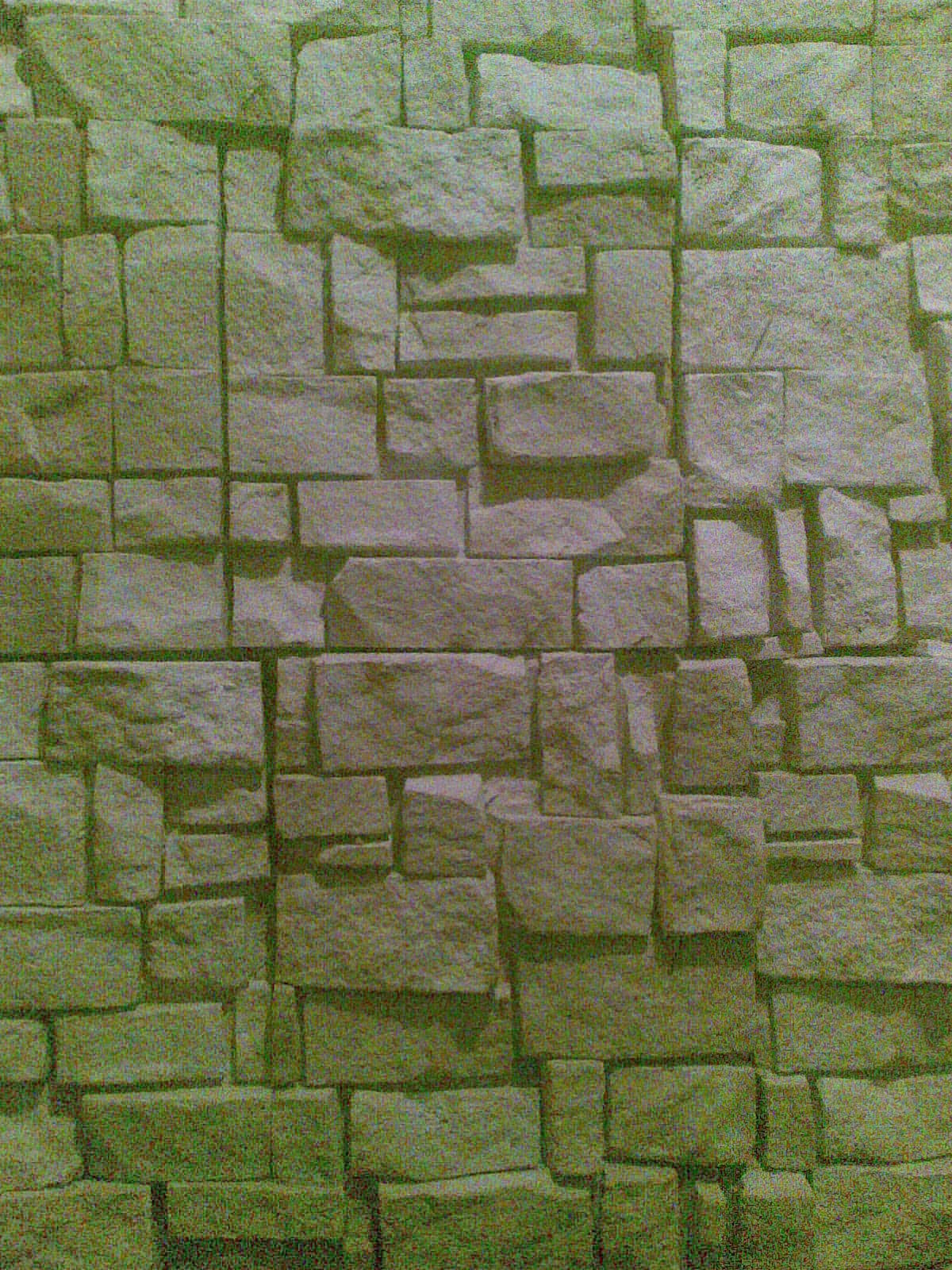 Tekstura ściany z płytek elewacyjnych imitujących kamień naturalny w odcieniach szarości i beżu, z widocznymi spoinami.