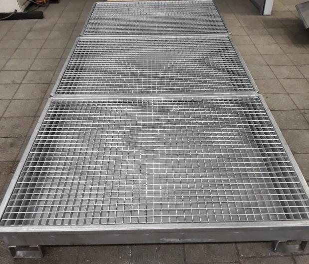 Trzy metalowe, kwadratowe kraty podłogowe z niskoprofilowymi nóżkami, ułożone jedna za drugą na szarej posadzce w hali.