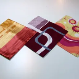 Trzy kwadratowe poszewki na poduszki z różnymi wzorami: abstrakcyjne kształty, paski i retro okręgi, ułożone na białym tle.