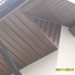 Brązowa podbitka dachowa z widocznym systemem rynnowym, zamontowana przy białej ścianie budynku. Ujęcie z dołu, ukazujące detale konstrukcji.