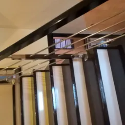 Metalowa poręcz schodowa z poziomymi prętami, czarne obramowanie stopni z białymi wypełnieniami, widok z góry.