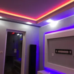 Nowoczesne wnętrze pokoju z podświetlanym sufitem w kolorach czerwieni i błękitu, szare ściany, czarny grzejnik i rama pod telewizor na ścianie.