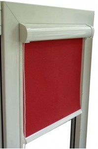 Czerwona roleta materiałowa zwinięta częściowo w białej ramie okiennej z widocznym mechanizmem łańcuszkowym.