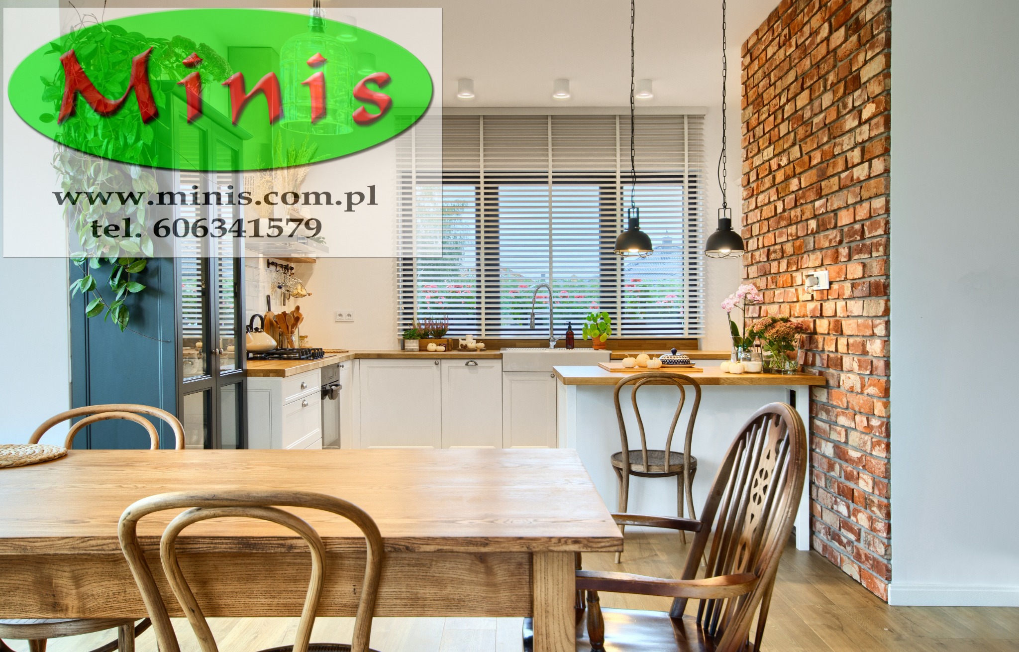 Wnętrze kuchni z drewnianym stołem i krzesłami, ceglaną ścianą oraz oknem z żaluzjami poziomymi; widoczne logo firmy nałożone na obraz.