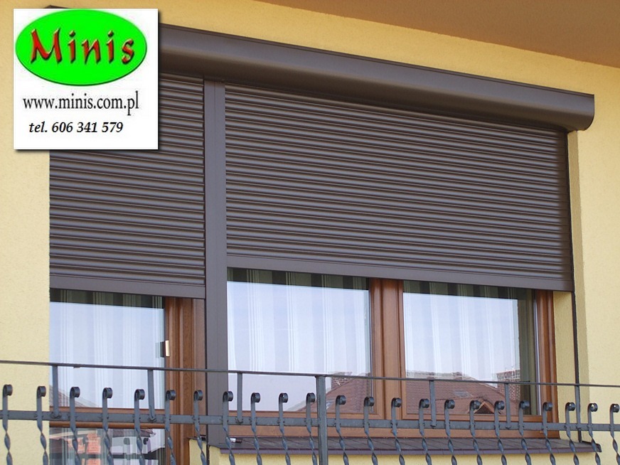Brązowa, zewnętrzna osłona okienna zamontowana na balkonie w Opolu, widoczna z zewnątrz budynku, z logo producenta w lewym górnym rogu.