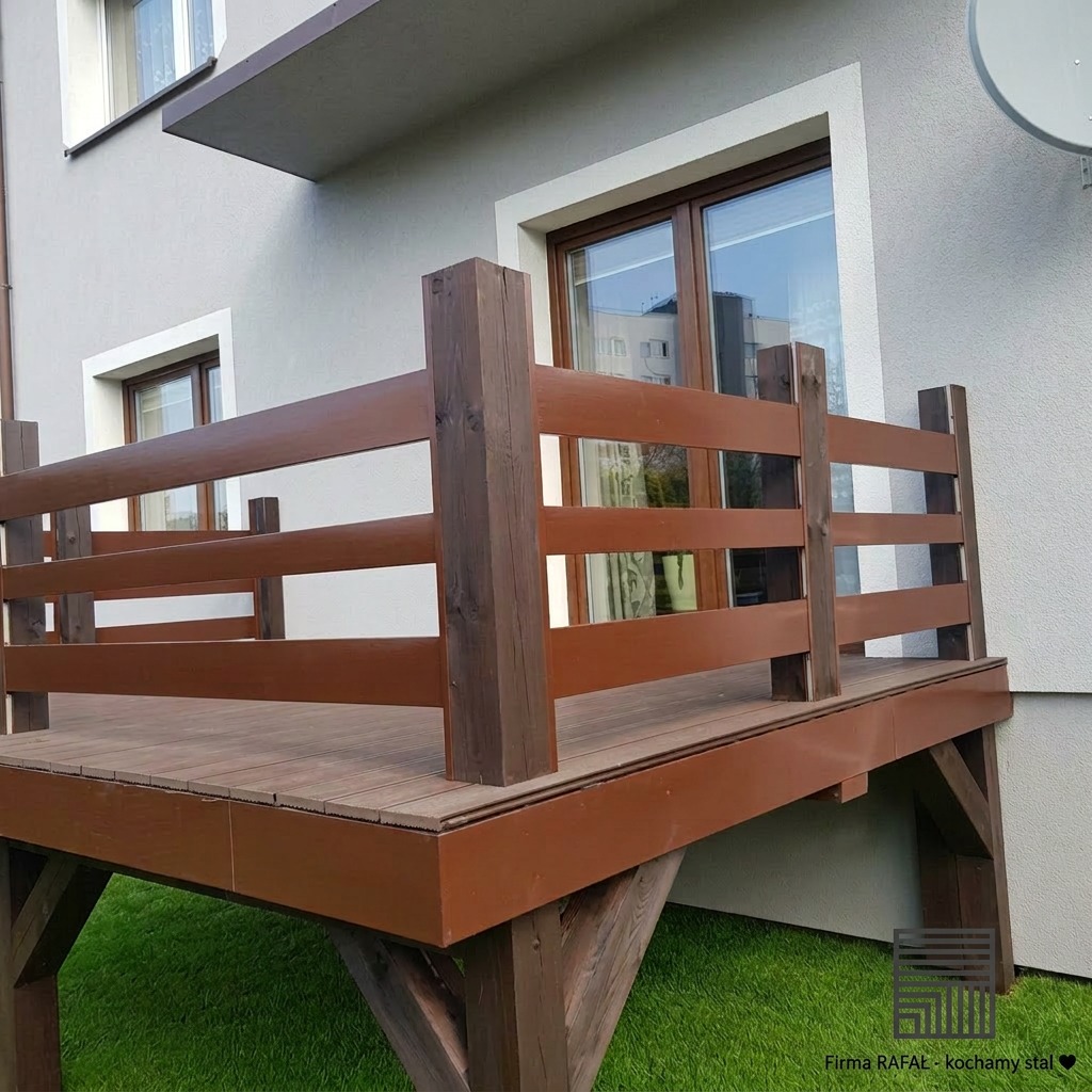 Drewniany balkon z brązową balustradą, widok z dołu na tle jasnej elewacji domu i sztucznej trawy. Ujęcie z boku, widoczne okna i satelita na ścianie.